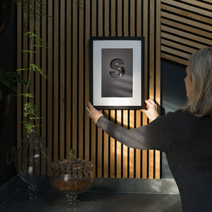 Lady hanging an Oh So framed pet picture on a modern looking wall