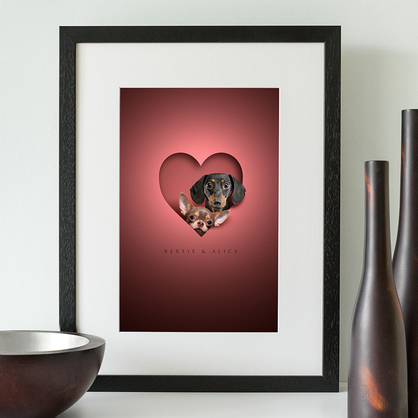 Modern pet picture of two cute dogs sitting in a cutout style heart shape creating an unusual 3d look. Ruby red background and a wooden black frame.