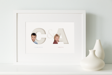 Load image into Gallery viewer, white framed picture of two children, each one sitting inside the initial letter of their name and their full name written below in a classy serif font