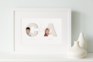 white framed picture of two children, each one sitting inside the initial letter of their name and their full name written below in a classy serif font